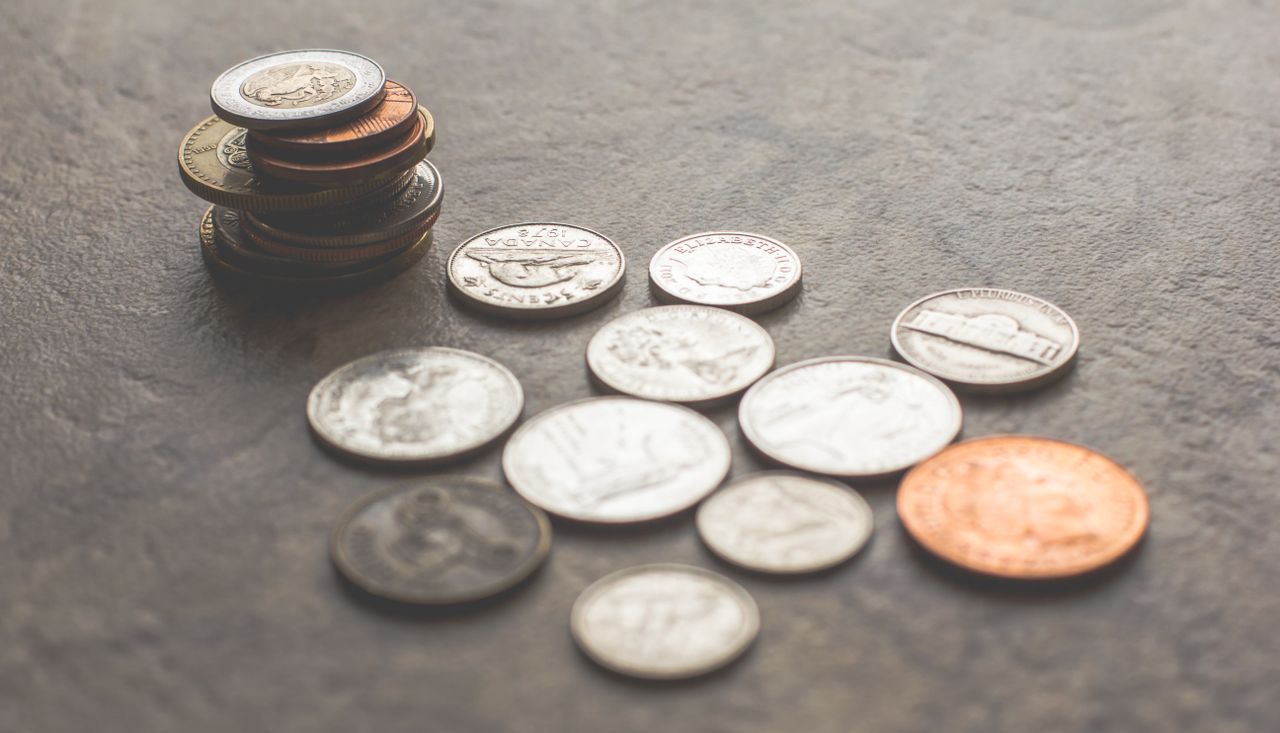 gallery-06 Assorted foreign coins stacked and scattered on a textured surface.