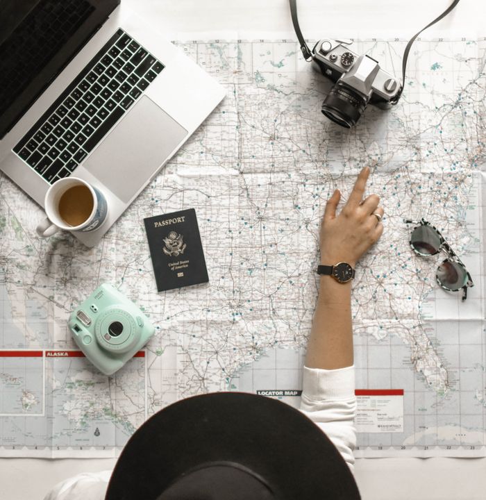 portfolio-01 Hand on map with camera, passport, laptop, and coffee, perfect for travel planning inspiration.