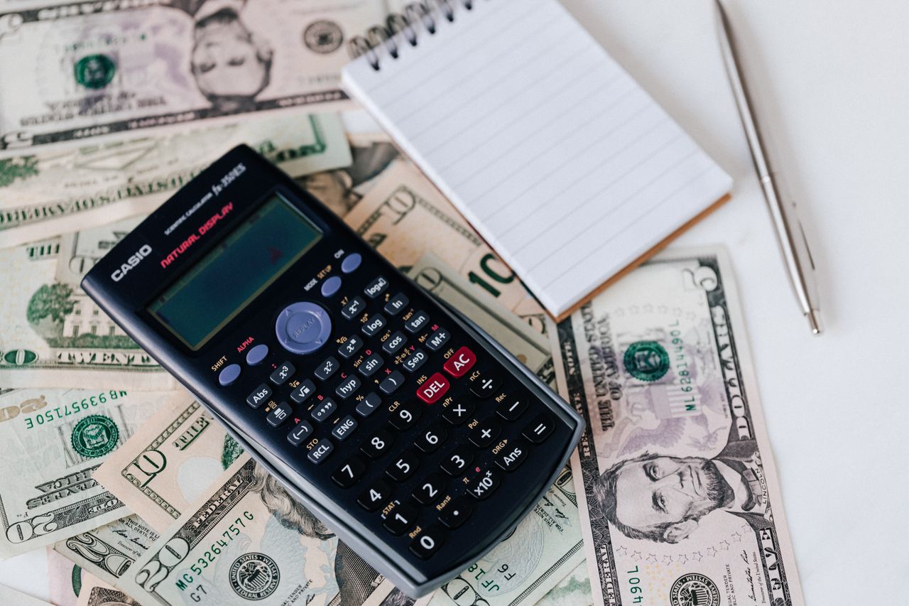 services-02 From above electronic calculator and notepad placed over United States dollar bills together with metallic pen for budget planning and calculation