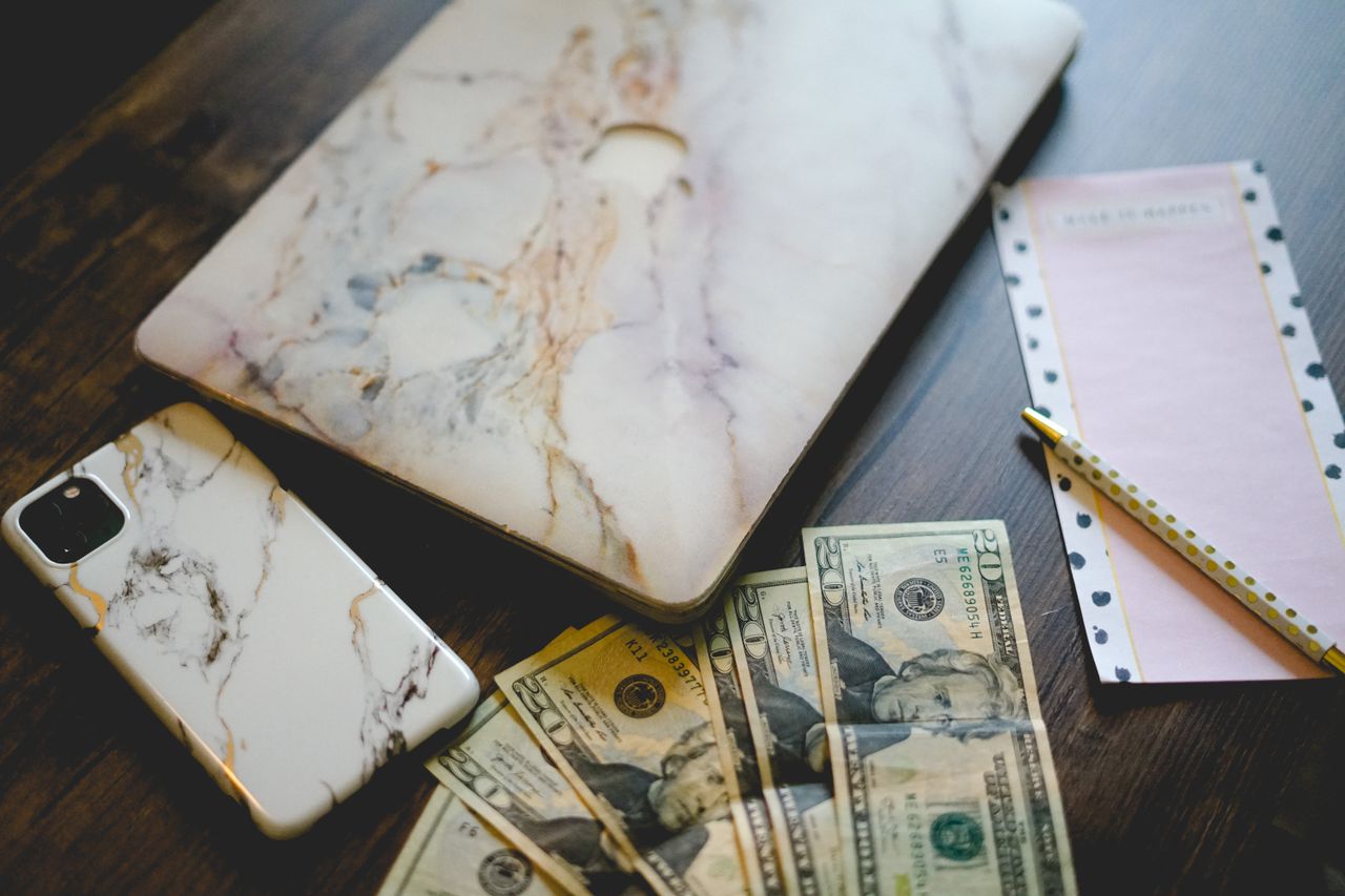 gallery-01 Stylish workspace with marble tech accessories, US currency, and a notepad on a wooden desk.