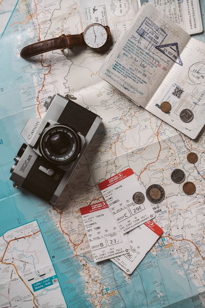 portfolio-07 Flat lay travel essentials including passports, tickets, and a vintage camera on a world map.