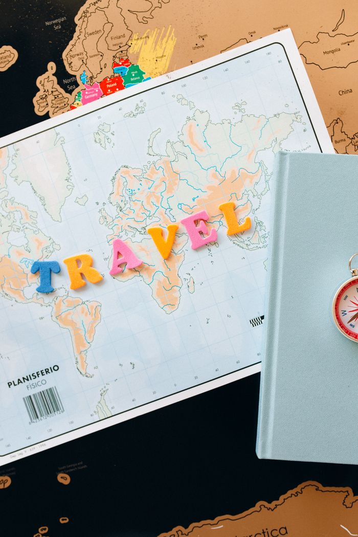portfolio-01 Vibrant travel arrangement featuring a world map, colorful letters, and a compass for adventure planning.